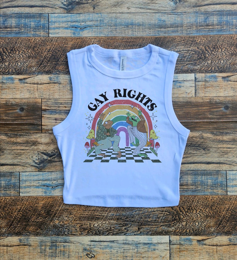 May include: White sleeveless crop top with a graphic print of two frogs dancing under a rainbow with the text "Gay Rights".