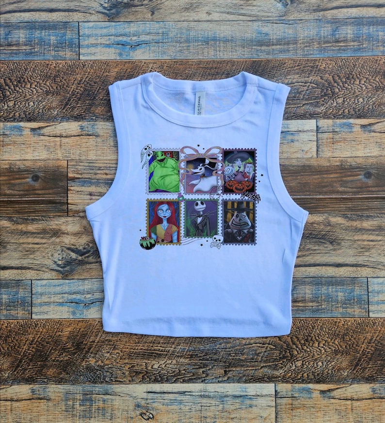 May include: White sleeveless crop top featuring a colorful graphic of postage stamps with characters from The Nightmare Before Christmas. The stamps include images of characters like Jack Skellington, Sally, and Oogie Boogie.