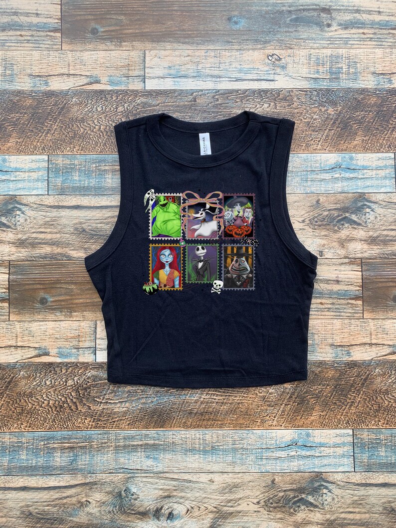May include: Black sleeveless crop top featuring a colorful graphic of postage stamps with characters from a popular animated movie. The stamps include images of a green monster, a skeleton, and a rag doll.
