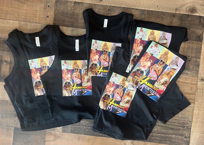 May include: Four black tank tops and a black t-shirt with a collage of images of Miley Cyrus as Hannah Montana. The images are in a grid pattern and include a variety of poses and outfits. The text "Hannah Montana" is printed in gold letters below the images.