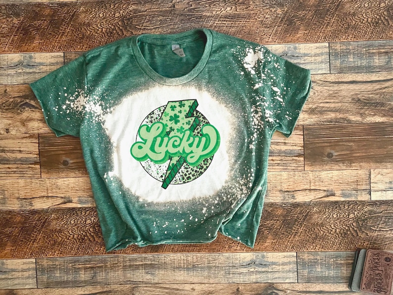 May include: Green t-shirt with a bleach design featuring a lightning bolt with shamrocks and the word "Lucky" in a retro font.
