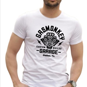 Pode incluir: Camiseta branca com um gr&aacute;fico preto de um motor estilizado com o texto "Gas Monkey Custom Builds -Garage- Dallas, Tx."