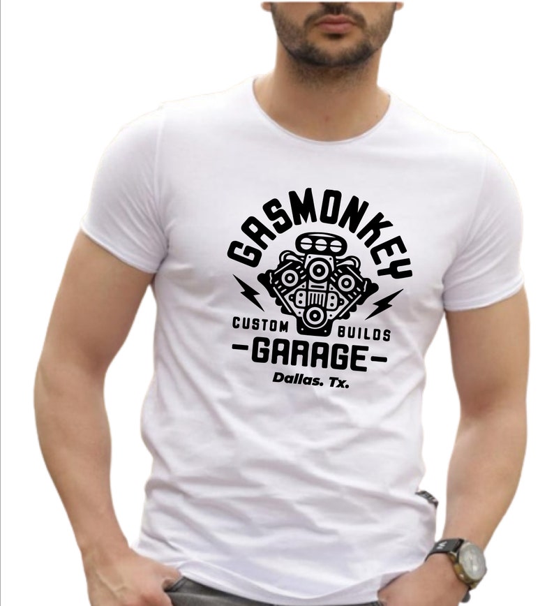 Pode incluir: Camiseta branca com um gr&aacute;fico preto de um motor estilizado com o texto "Gas Monkey Custom Builds -Garage- Dallas, Tx."