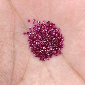 Pode incluir: Um monte de pequenas pedras preciosas de rubi vermelho brilhante, provavelmente para a fabricação de joias.