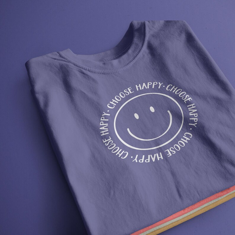 K&ouml;nnte beinhalten: Lilafarbenes T-Shirt mit einem wei&szlig;en Smiley und dem Text "Choose Happy. Choose Happy. Choose Happy. Choose Happy."