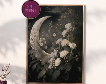May include: A crescent moon art print with white flowers and greenery on a dark background. The moon is a light beige color and the flowers are white with a hint of pink. The background is a dark green and black.