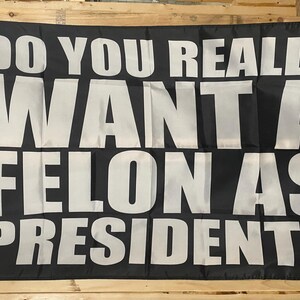 May include: Black and white flag with the text "Do you really want a felon as president?" in white letters.
