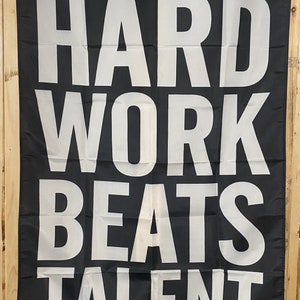 May include: Black flag with white text that reads "HARD WORK BEATS TALENT".