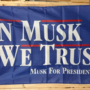 May include: A blue flag with white text that reads "IN MUSK WE TRUST" with a red line above and below the text. Below the text is "Musk For President '28" in white. The flag is rectangular.