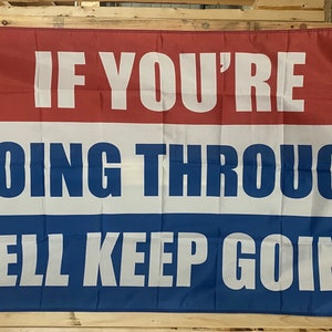 May include: A red, white and blue flag with the text "If you're going through hell keep going" in white letters.