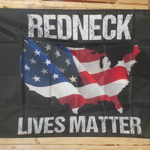 Könnte beinhalten: Schwarze Flagge mit einer weißen Umrandung der Vereinigten Staaten von Amerika mit roten und weißen Streifen und blauen Sternen. Der Text "REDNECK LIVES MATTER" ist in weiß auf der Flagge gedruckt.