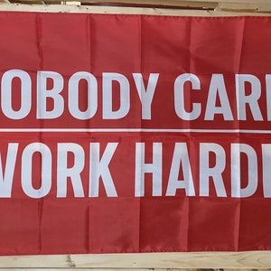 Peut inclure: Drapeau rouge avec du texte blanc qui dit "Nobody Cares Work Harder".