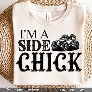 May include: White t-shirt with black text that reads "I'm a Side by Side Chick" and a black and white illustration of a side-by-side vehicle.