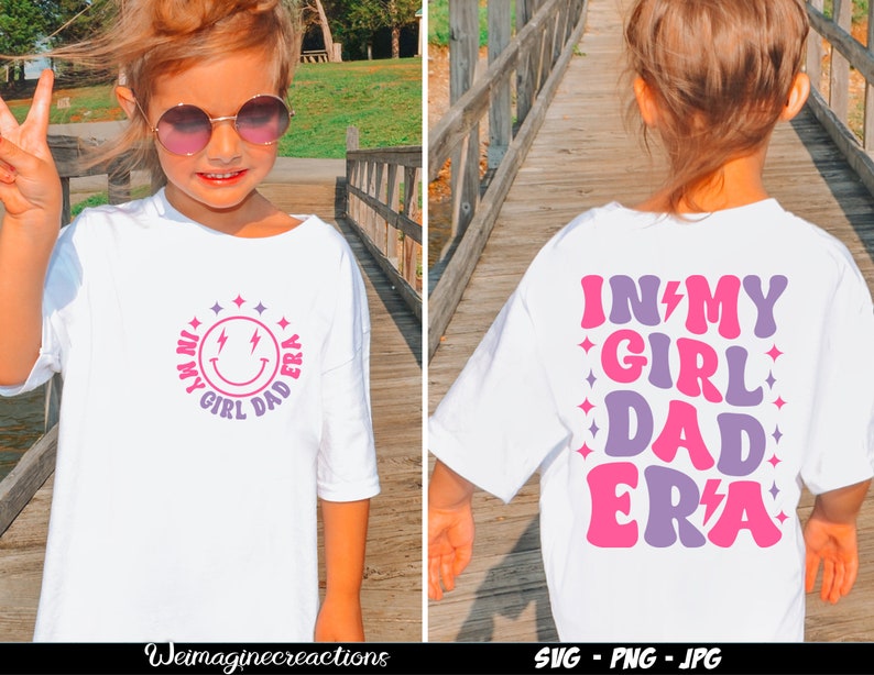 May include: A white t-shirt with a pink and purple design that says "In My Girl Dad Era" on the back and a smiley face with lightning bolts and the same text in a circle on the front.