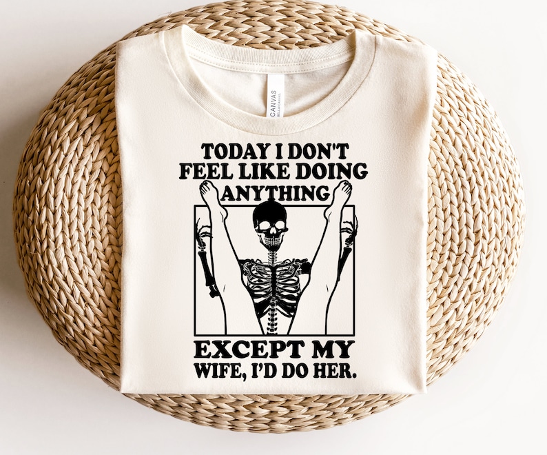 May include: A white t-shirt with a black graphic of a skeleton doing a yoga pose. The text on the shirt reads "Today I don't feel like doing anything except my wife, I'd do her."