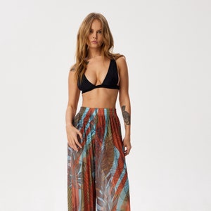 May include: A pair of wide-leg trousers with a colourful tropical print. The trousers are made of a lightweight, sheer fabric and have a relaxed fit.