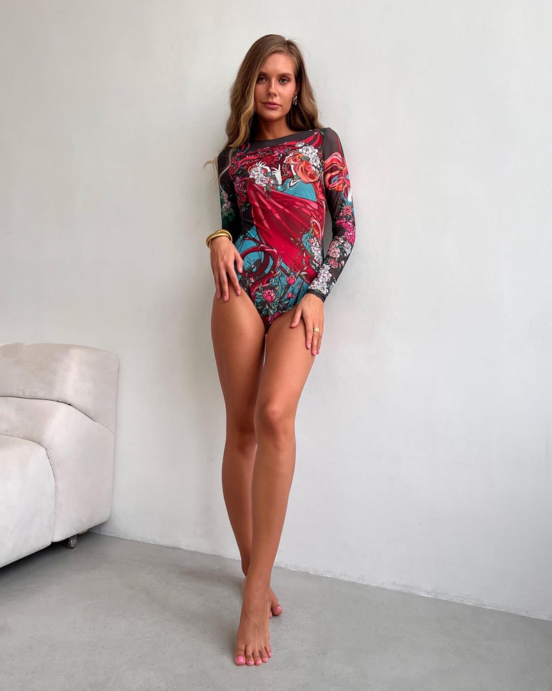 Peut inclure: Un body noir en maille avec un imprim&eacute; floral color&eacute; et des manches longues. Le body pr&eacute;sente un motif floral rouge, bleu et vert.