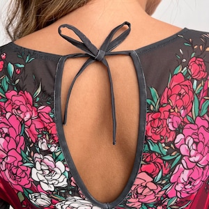 Peut inclure: Haut en maille noire &agrave; imprim&eacute; floral avec des fleurs roses, blanches et vertes. Le haut a un dos en forme de trou de serrure avec un ruban noir.