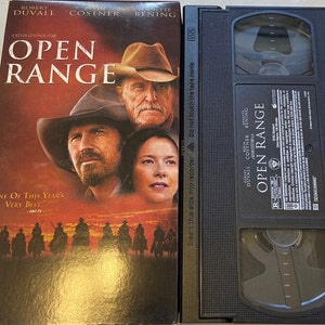 May include: VHS tape case for the movie "Open Range" starring Robert Duvall, Kevin Costner, and Annette Bening. The case is black with a red and white label featuring the movie title and actors' names.