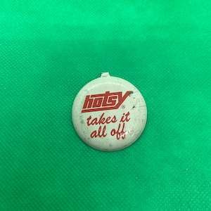 May include: A white round button with red text that reads "Hotsy takes it all off" with a registered trademark symbol.