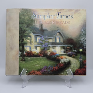 May include: A square art print titled "Simpler Times" by Thomas Kinkade. The artwork depicts a quaint yellow house with a porch, surrounded by a lush garden with a stone pathway. The sky is a soft, muted color.