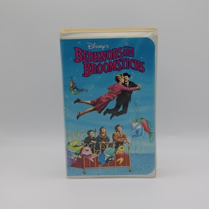 May include: A VHS tape case with a blue background featuring a scene from the Disney movie Bedknobs and Broomsticks. The case has the title "Disney's Bedknobs and Broomsticks" printed in white.