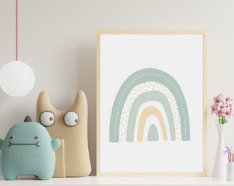 Pode incluir: Uma impressão emoldurada de um arco-íris com um esquema de cores azul claro, verde e amarelo. O arco-íris tem um padrão de pontos e um contorno costurado. A impressão está pendurada em uma parede branca com dois brinquedos de pelúcia na frente.