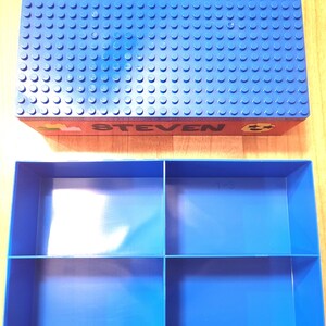 May include: Blue plastic storage box with a blue Lego base plate lid. The lid has the name "STEVEN" printed on it. The box has four compartments inside.