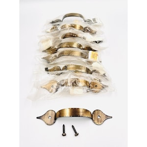 May include: A collection of antique-style brass cabinet handles. The handles have a decorative hammered texture and ornate end pieces. Two screws are included with one handle. The handles are packaged in clear plastic.