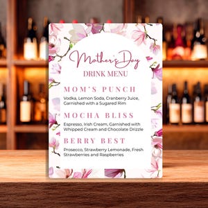 Può includere: Un menu di bevande per la festa della mamma con un design floreale. Il menu elenca tre opzioni di bevande: Mom's Punch, Mocha Bliss e Berry Best. Il menu è bianco con accenti floreali rosa ed è esposto su una superficie di legno.