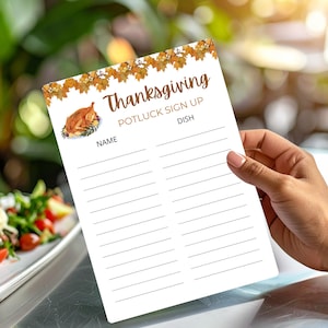 May include: A white Thanksgiving potluck sign-up sheet with a roasted turkey illustration and fall leaf border. The sheet includes spaces for names and dishes. The image is held by a person.