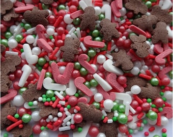 May include: A mix of red, white, green, and brown sprinkles in the shape of candy canes, gingerbread men, and small balls.