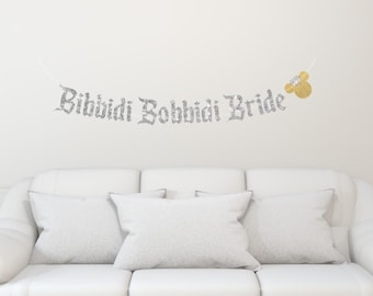May include: Silver glitter banner with the text "Bibbidi Bobbidi Bride" and a gold glitter Mickey Mouse head.