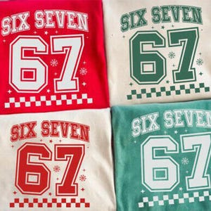May include: Four t-shirts with the text "SIX SEVEN" and the number "67" in a collegiate style. The shirts are in red, green, cream, and teal. Each shirt has a checkered pattern at the bottom and snowflake accents.