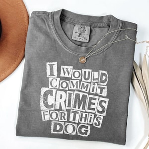 May include: A charcoal grey short-sleeve t-shirt featuring the white distressed text I WOULD COMMIT CRIMES FOR THIS DOG printed on the front. The shirt has a crew neckline and a Comfort Colors brand label on the inside collar showing size S-P-CH.