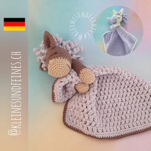 Può includere: Una copertina per neonati in crochet di colore lavanda con un giocattolo di cavallo in crochet marrone e bianco. La copertina ha un bordo marrone e il cavallo è sdraiato sopra la copertina. La copertina è un ottimo regalo per un neonato.
