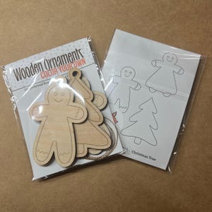 May include: Two packages of wooden Christmas ornaments. One package contains unfinished gingerbread boy and tree shapes with the text "Wooden Ornaments COLOR YOUR OWN". The other package contains outlines of gingerbread men and Christmas trees.