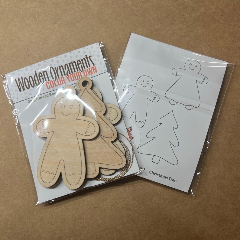 May include: Two packages of wooden Christmas ornaments. One package contains unfinished gingerbread boy and tree shapes with the text "Wooden Ornaments COLOR YOUR OWN". The other package contains outlines of gingerbread men and Christmas trees.