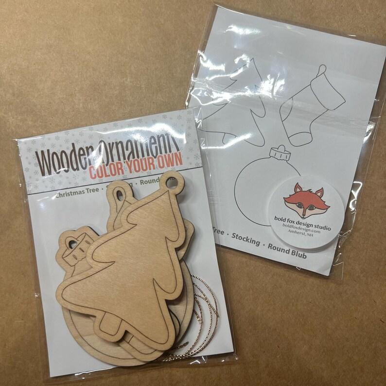 May include: Two packages of wooden Christmas ornaments. One package contains unfinished wooden ornaments in the shape of a Christmas tree and a round ornament. The other package contains line drawings of a Christmas tree, stocking, and round ornament.