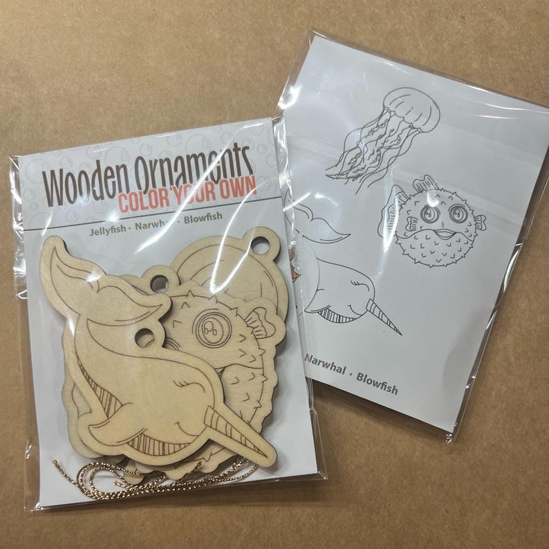 May include: Wooden ornaments in the shape of a jellyfish, narwhal, and blowfish, ready to be colored. The package includes a string for hanging. A separate sheet shows line drawings of the same sea creatures.