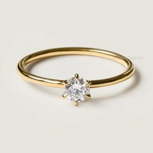 May include: A simple gold band ring with a single round diamond set in a six-prong setting.