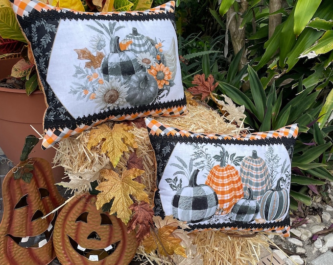 Decorative throw pillows with gray and orange autumn scene fabric and black trim