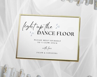 May include: A gold-framed sign with the text "light up the DANCE FLOOR" in elegant script. The sign also includes the text "PLEASE HELP YOURSELF TO A GLOW STICK with love JACOB & SAMANTHA". White glow sticks are visible.