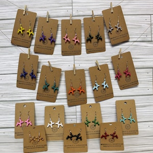 May include: Assortment of balloon dog dangle earrings on brown card stock with the text "Mammie's Memories" printed on each card. The earrings are available in a variety of colors, including yellow, purple, pink, green, blue, red, orange, white, black, and silver.