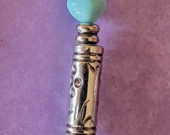 May include: A colorful beaded necklace with a silver charm featuring a floral design. The beads are blue, green, orange, yellow, and white.