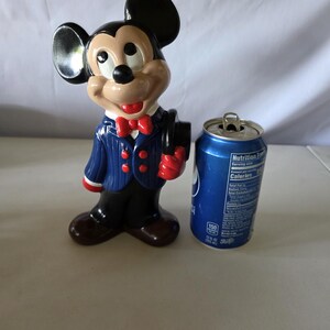 K&ouml;nnte beinhalten: Eine Keramikfigur von Mickey Mouse in einem blau gestreiften Anzug, roter Fliege und schwarzem Zylinder. Daneben steht eine blaue Pepsi-Dose.