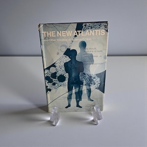 May include: A vintage paperback book titled "THE NEW ATLANTIS" with a blue and white cover design. The cover features silhouettes of two figures and the names of the authors: Gene Wolfe, Ursula K. Le Guin, and James Tiptree, Jr.