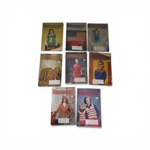 May include: A collection of eight vintage Workbasket magazines featuring various cover illustrations, including people wearing knitted garments, a large American flag, and a textured blanket, all arranged in a grid against a plain white background.