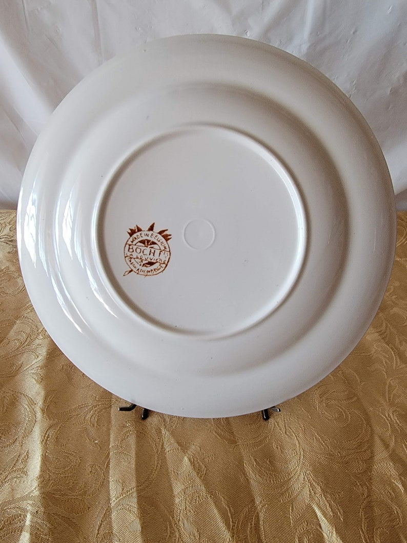May include: White ceramic plate with a brown rim and a brown logo that reads "Made in Belgium Boch Fr&egrave;res" in a circle.