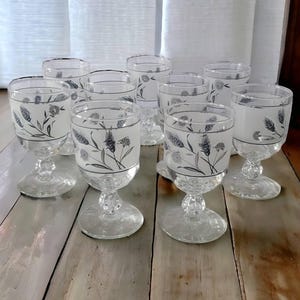 May include: Set of ten frosted glass goblets with silver floral designs. The goblets have a clear base and a frosted bowl with a silver band around the top.